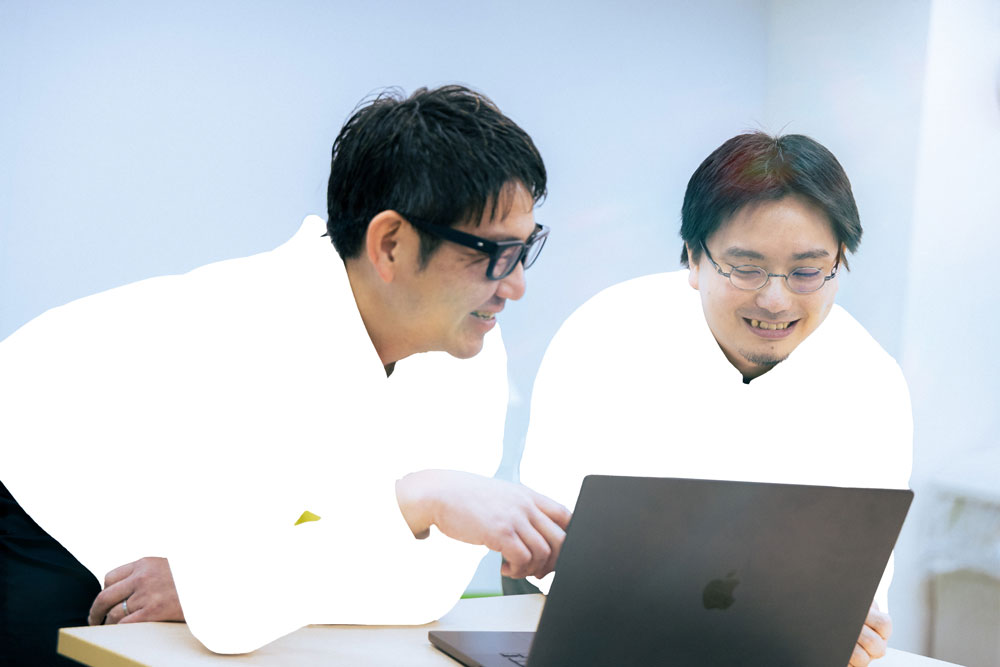 ノートPCを使って共同作業するホワイトプラスの社員2名